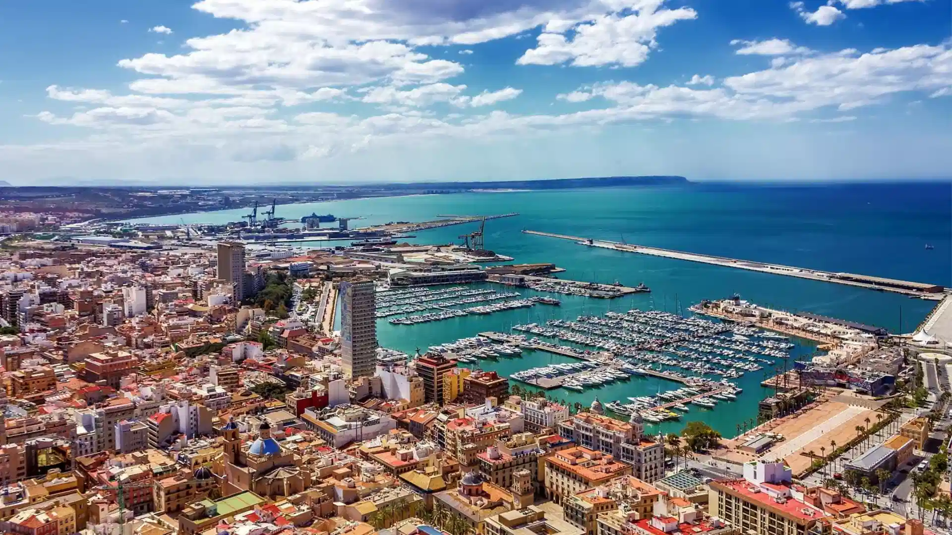 Aerial view of a coastal city with marina and turquoise sea