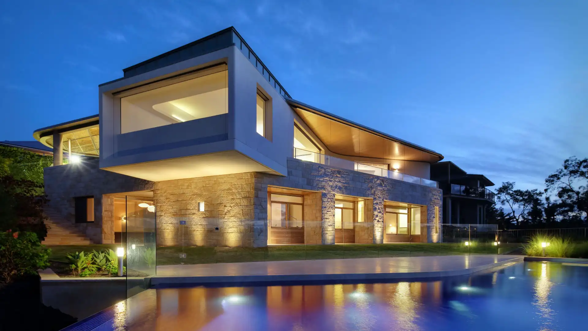 Modern luxury villa with evening lighting and glass-fronted design