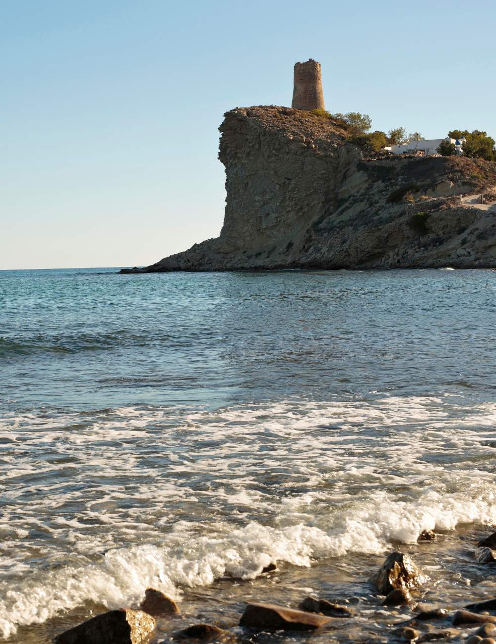 Waves crashing near the rocky coast and 16th-century watchtower in Villajoyosa