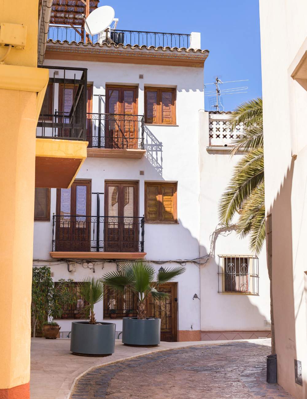 Narrow street with Mediterranean-style balconies and potted plants in Finestrat