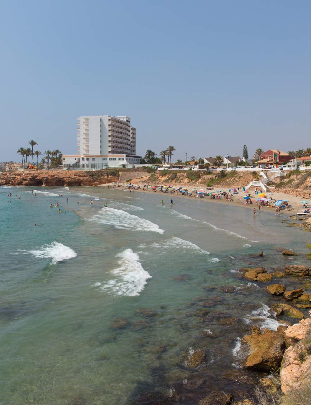 Swimmers enjoy the waves at Playa Cala Cerrada in Orihuela Costa